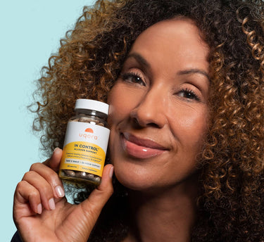 Curly woman smiling holding In Control bottle