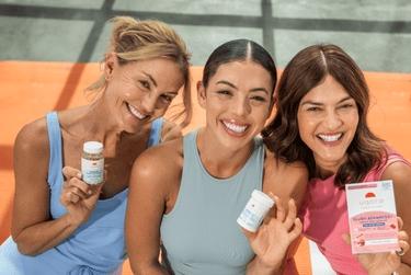 Three smiling women holding Uqora products on an orange yoga mat